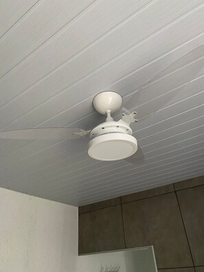 A ceiling fan in a room with a tiled floor and a wall-mounted mirror. - Gyn Suítes Universitário (Goiânia)
