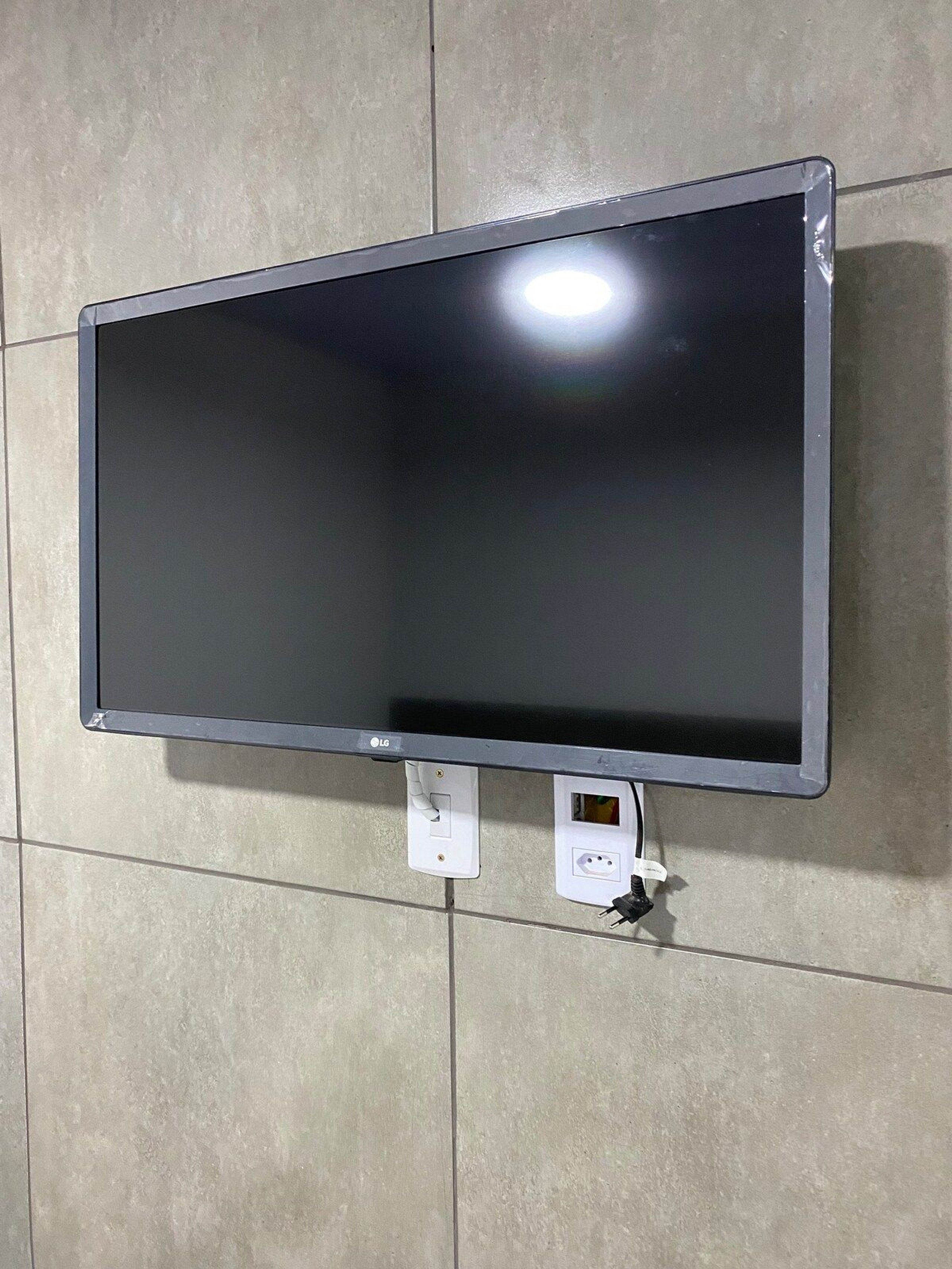 Un téléviseur à écran plat fixé sur un mur recouvert de carreaux.