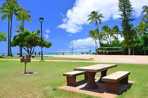 A park with picnic tables, a volleyball net, and palm trees. - Gorgeous Ocean Views in the Heart of Waikiki! Full Kitchen, Free Wi-Fi & More (Honolulu)