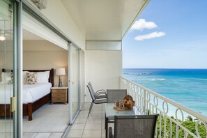 Ein Balkon mit einem Bett, einem Tisch und einem Korb, mit Blick auf das Meer.