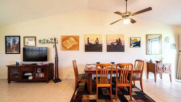 A dining area with a table set for four, a television, and artwork on the walls.