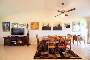 Un comedor con una mesa dispuesta para cuatro personas, un televisor y obras de arte en las paredes.