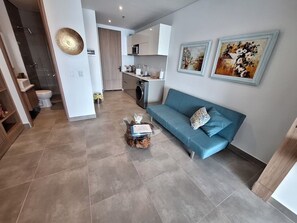 Ein modernes Wohnzimmer mit einem blauen Sofa, einem Couchtisch und Kunstwerken an der Wand.