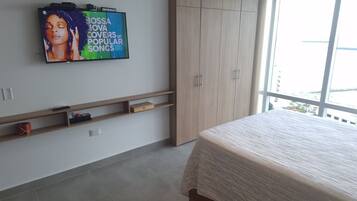 Une chambre à coucher comprenant un lit, un téléviseur fixé au mur, une armoire et une fenêtre donnant sur un paysage.