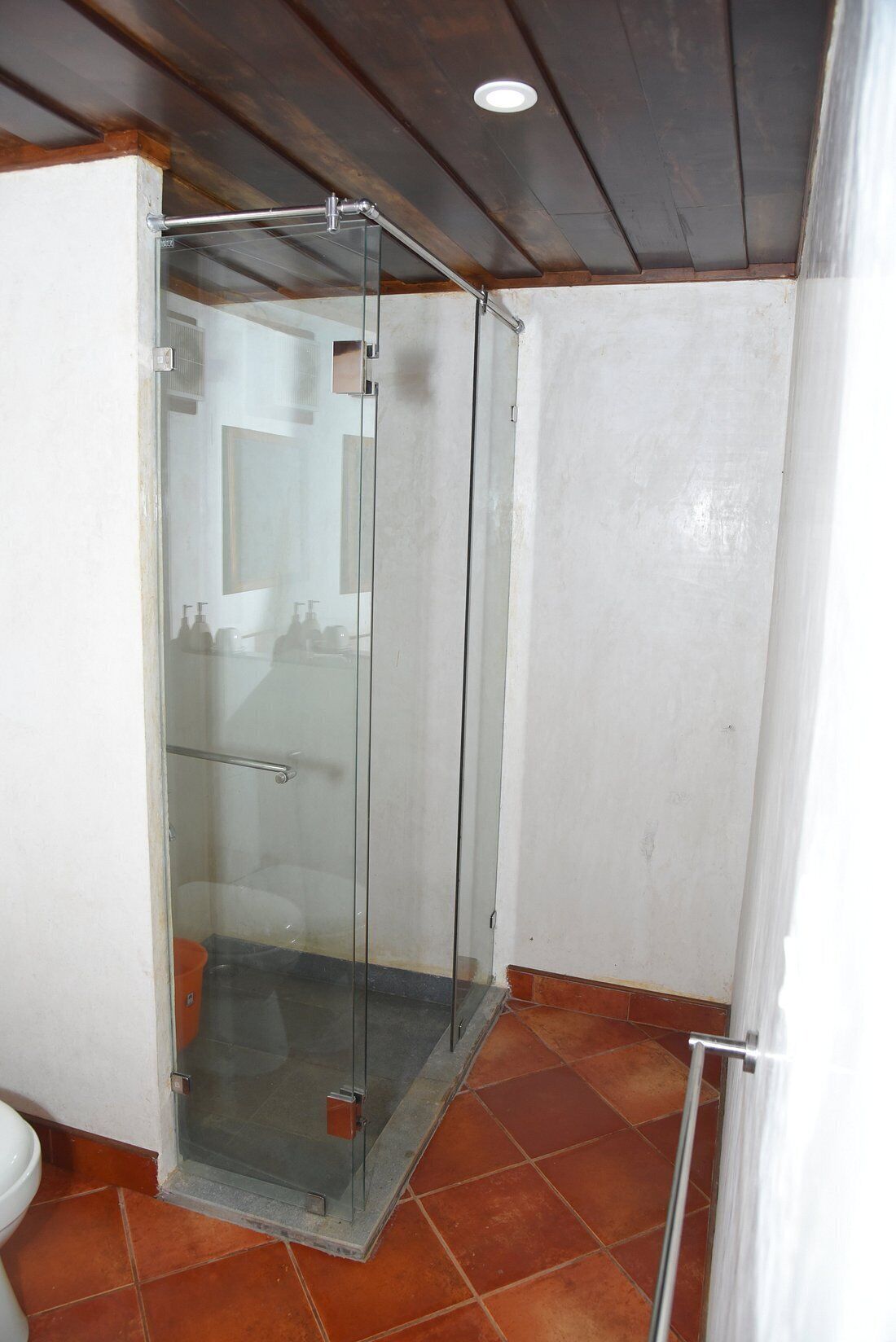 Un baño con cabina de ducha de vidrio, un inodoro y suelo de baldosas.