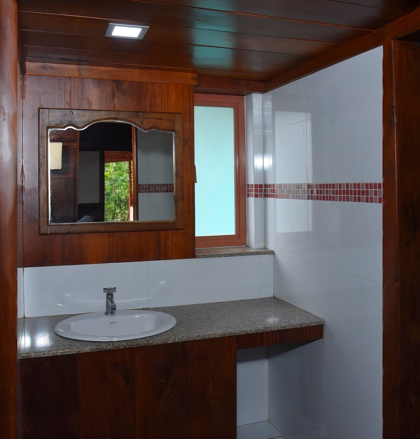 Ein Badezimmer mit einem Holzkonsolenunterschrank, einem Waschbecken, einem Spiegel und einem Fenster.