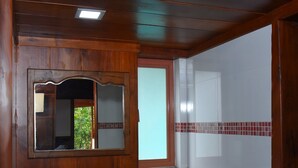 Un baño con tocador de madera, lavamanos, espejo y ventana.