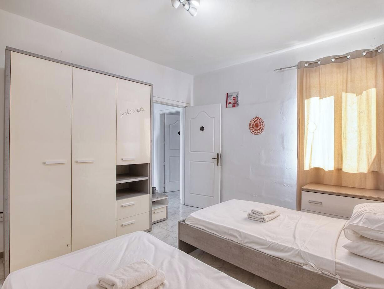 Una camera d'albergo con un letto, un armadio, una scrivania e l'ingresso del bagno.