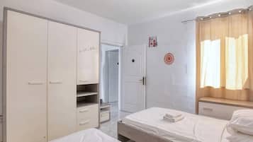 Una camera d'albergo con un letto, un armadio, una scrivania e l'ingresso del bagno.