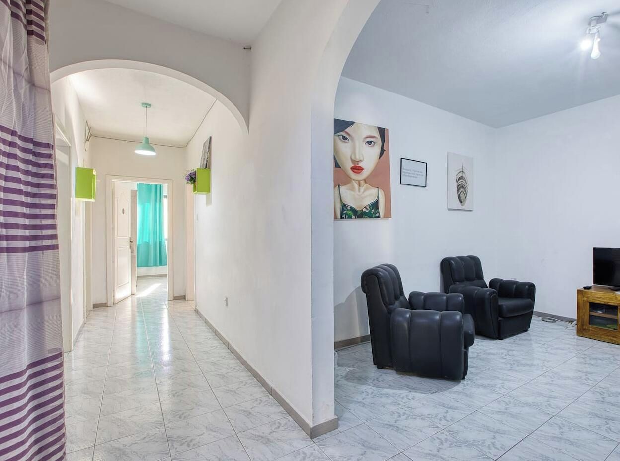 A spacious living area with a seating arrangement, a television, and artwork on the walls.