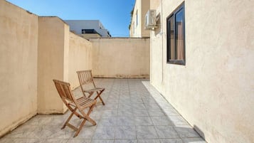 Un'area patio esterna con due sedie di legno e un pavimento piastrellato.