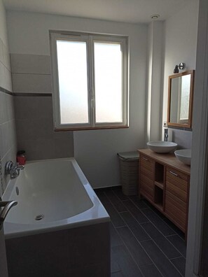Ein Badezimmer mit einer Badewanne, einem Waschbecken mit Spiegel und einem Fenster.