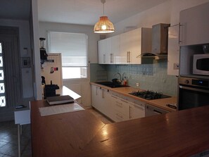 A modern kitchen with white cabinets, a wooden countertop, a gas stove, and a microwave. - House for 8 people •Jacuzzi Spa• Garden• Parking • Air Conditioning (Avignon)