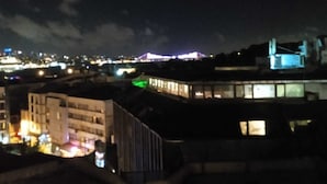 Eine beleuchtete Stadtlandschaft bei Nacht mit Gebäuden und einer Brücke.