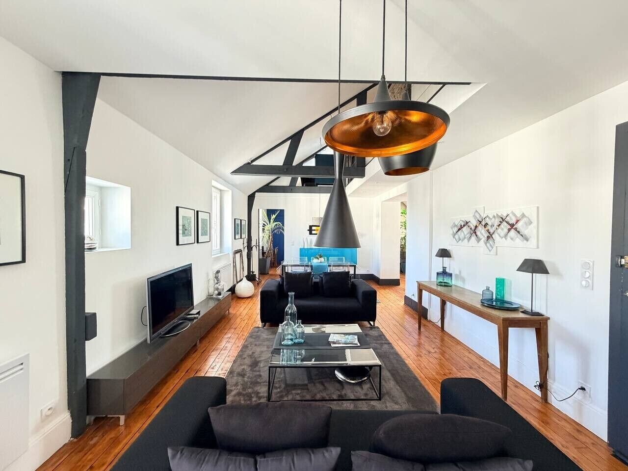 A modern living room with a sofa, coffee table, and pendant lighting.