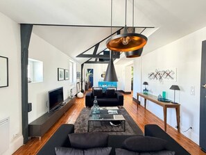 Een moderne woonkamer met een bank, salontafel en hanglampen.