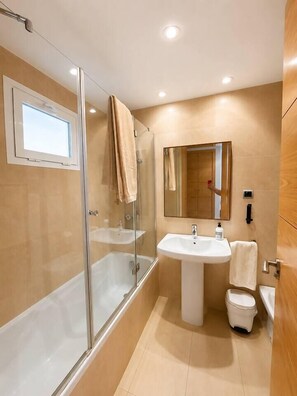 A modern bathroom with a glass-enclosed shower, a white sink, and a toilet. - Vrbo Property (Alcazares, Los)