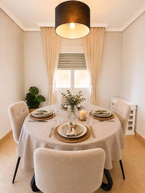 A dining area with a round table set for four, surrounded by chairs. - Serena Golf Views • Beach & Golf Apartment (Alcazares, Los)