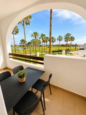 A balcony with a view of palm trees and a golf course. - Vrbo Property (Alcazares, Los)