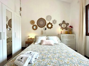 Un dormitori amb llit, un taulell de nit, un armari i decoracions murals.