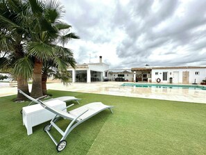 Una casa moderna amb piscina, un porxo cobert i un jardí amb dues gandules.