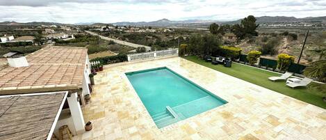 A rooftop pool with a view of a residential area and distant hills.
