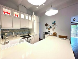 Eine moderne Küche mit weißen Schränken, einer zentralen Kochinsel und einer Küchenrückwand mit Zickzackmuster.