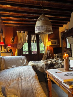 A cozy room with wooden beams, a bed with a fur throw, a hanging lamp, and a candle on a table. - Large wooden chalet in the heart of the Écrins (Saint-Jean-Saint-Nicolas)