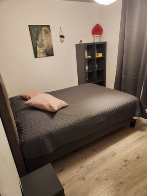 Ein Schlafzimmer mit einem Bett, einem Nachttisch, einem Regal mit Dekoration und einem Bild an der Wand.