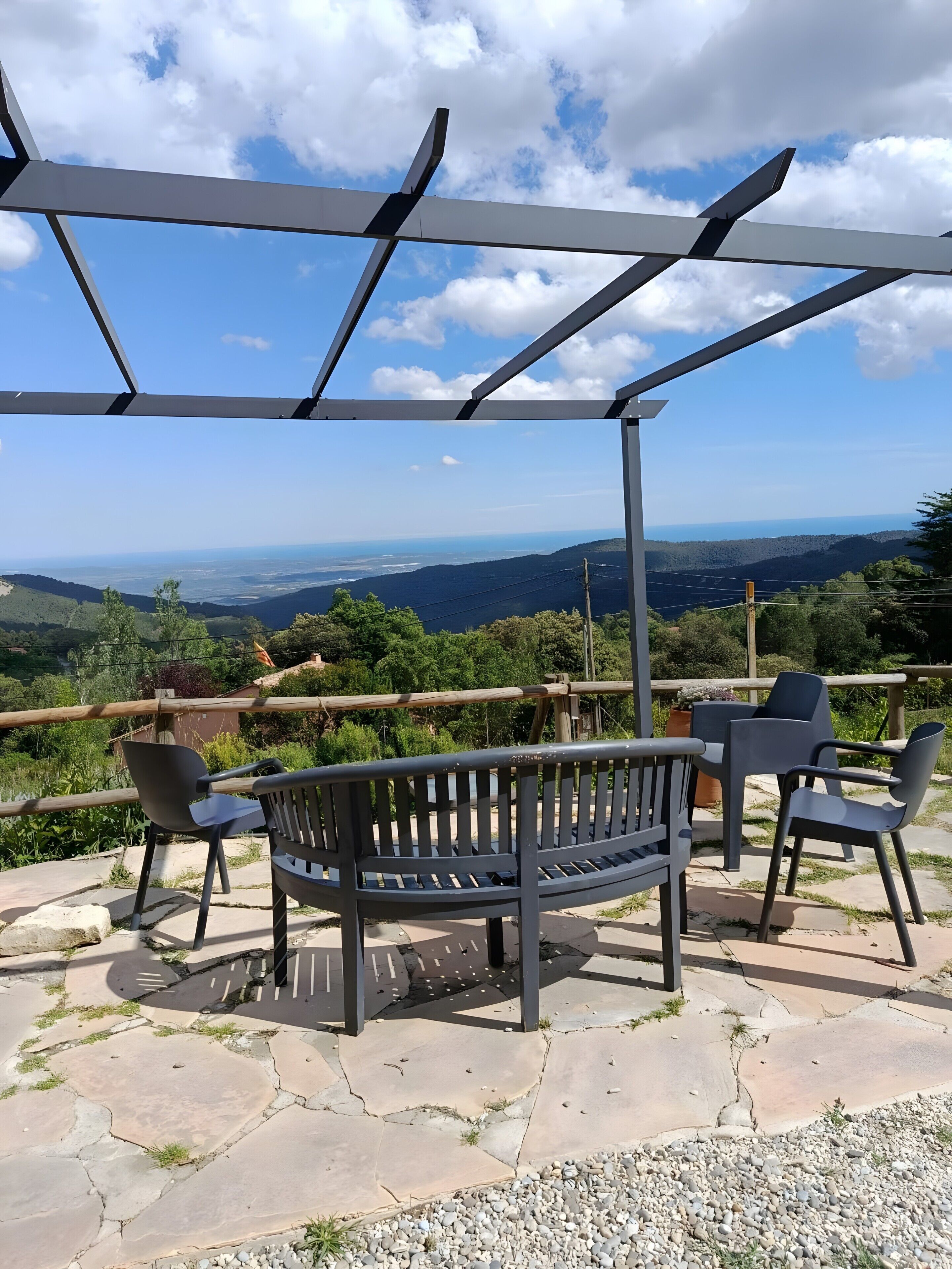 A bench under a pergola with a view of a mountainous landscape.