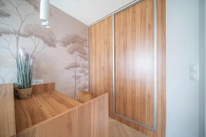 A modern interior with a wooden staircase, a wall-mounted plant, and a sliding door. - Kierbedzia Apart (Warszawa)