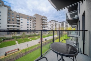 A balcony with a table and chairs, overlooking a residential area with multiple apartment buildings. - Kierbedzia Apart (Warszawa)