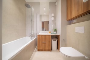 A modern bathroom with a bathtub, a shower, a sink, and a toilet. - Kierbedzia Apart (Warszawa)