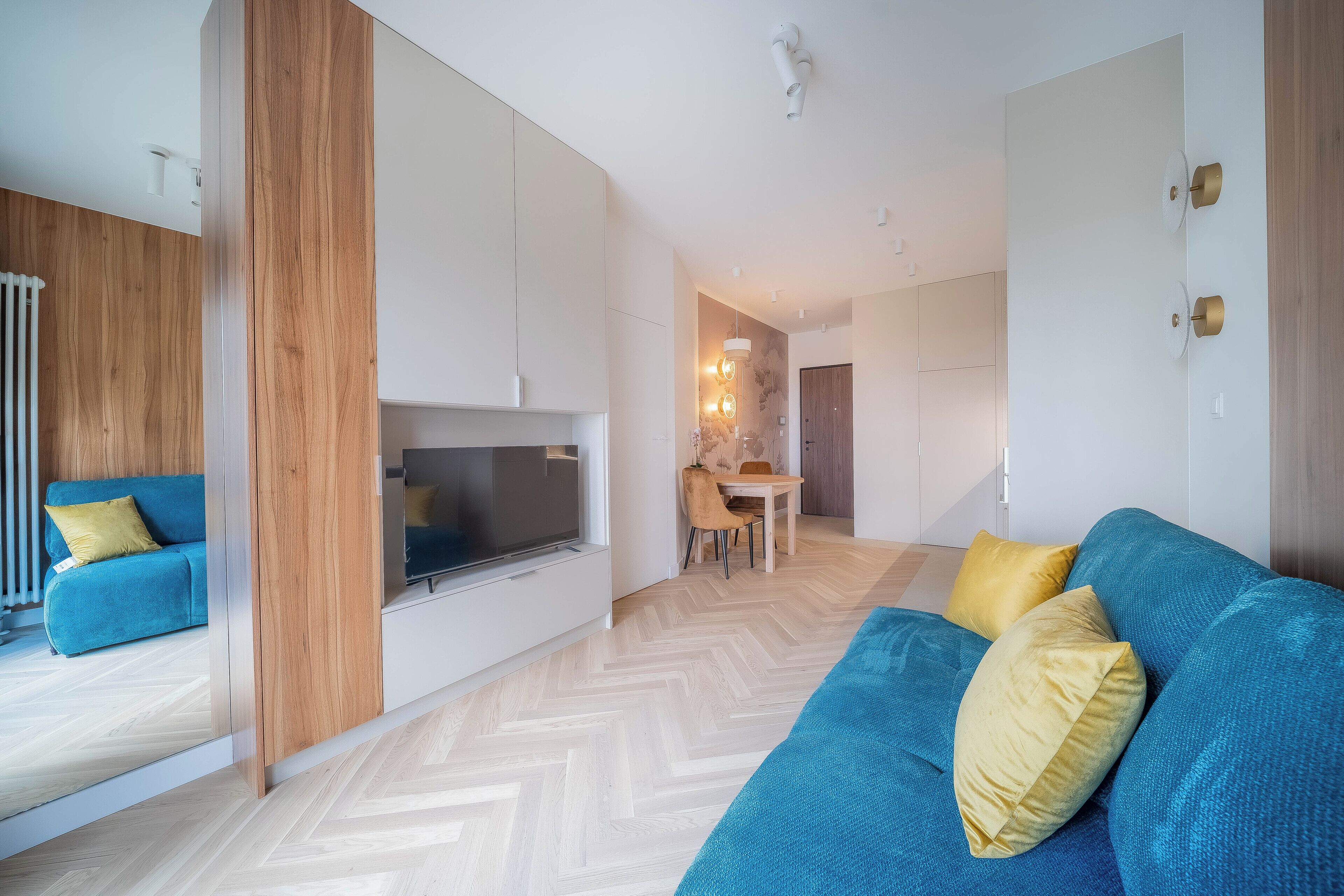 Uma sala de estar moderna com um sofá, uma televisão e um espaço de refeições com mesa e cadeiras.