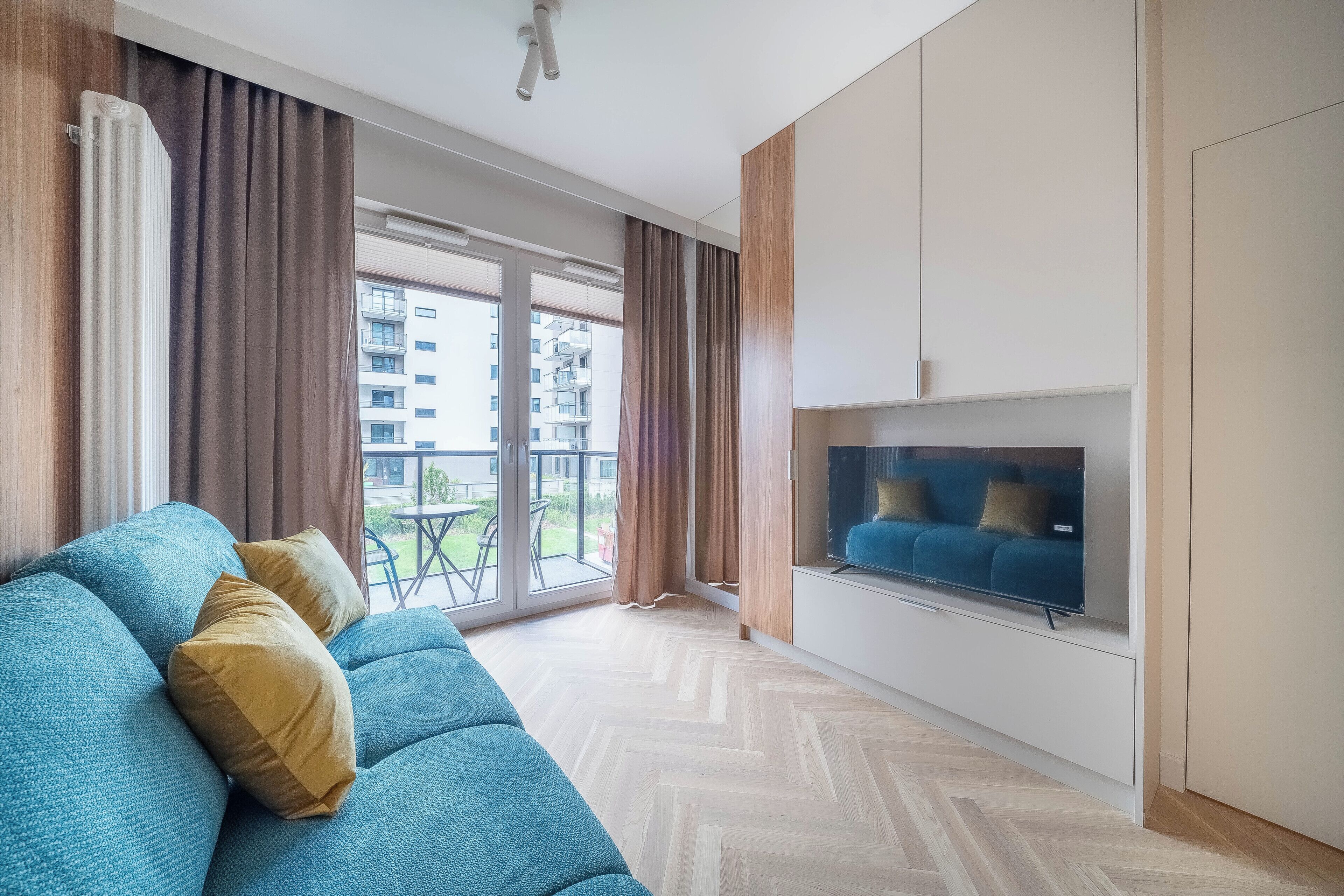 Un salon moderne avec un canapé, un téléviseur à écran plat et de grandes fenêtres.