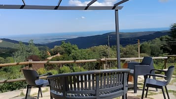 Banco y sillas bajo una pérgola con vista a un paisaje.