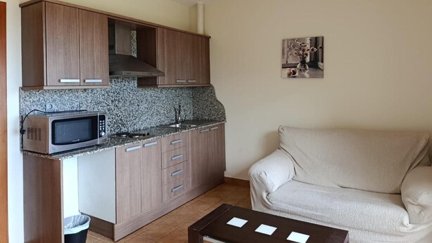 A compact kitchen with a microwave, cabinets, and a small dining area with a table and chair. - Apartment 'Apartament Cor De Prades' with Sea View, Balcony and Wi-Fi (Mont-ral)