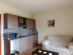 A compact kitchen with a microwave, cabinets, and a small dining area with a table and chair. - Apartment 'Apartament Cor De Prades' with Sea View, Balcony and Wi-Fi (Mont-ral)