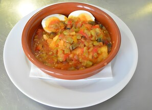 A bowl of soup with vegetables and a boiled egg on a white plate.