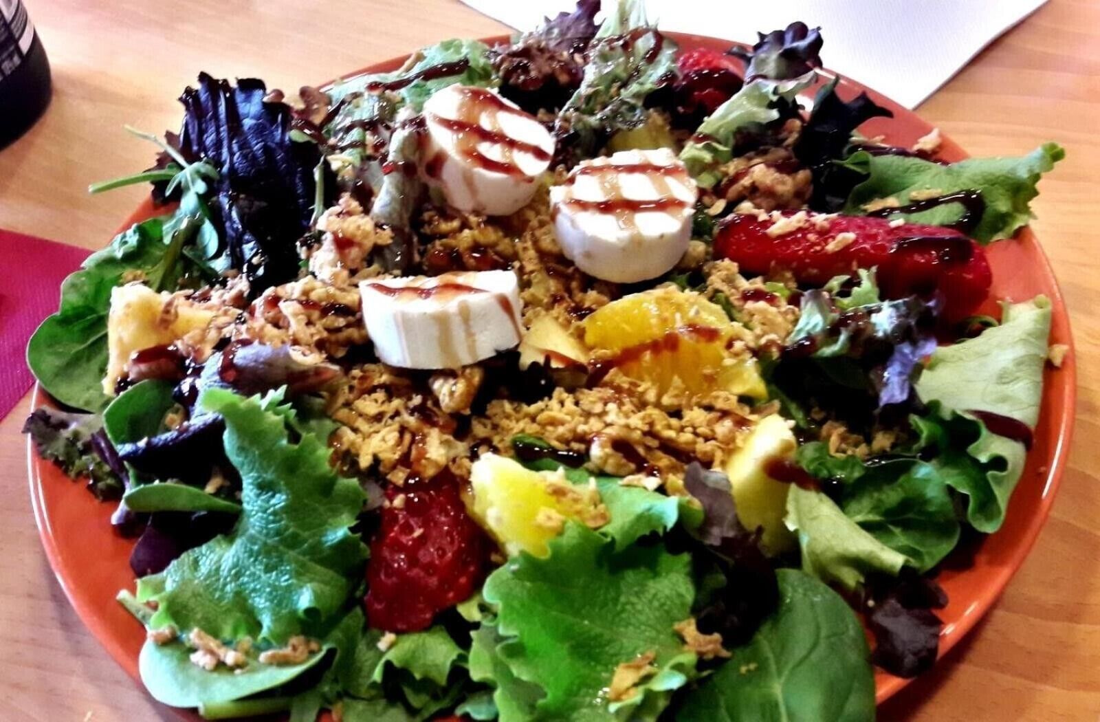 En sallad med olika tillbehör och en tallrik på ett bord.