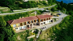 A two-story building with a red roof, multiple balconies, and a paved driveway. - Room 'Habitació Cirerer' with Sea View, Balcony and Wi-Fi (Mont-ral)
