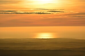 Eine Landschaft mit untergehender oder aufgehender Sonne über einer Hügelkette.