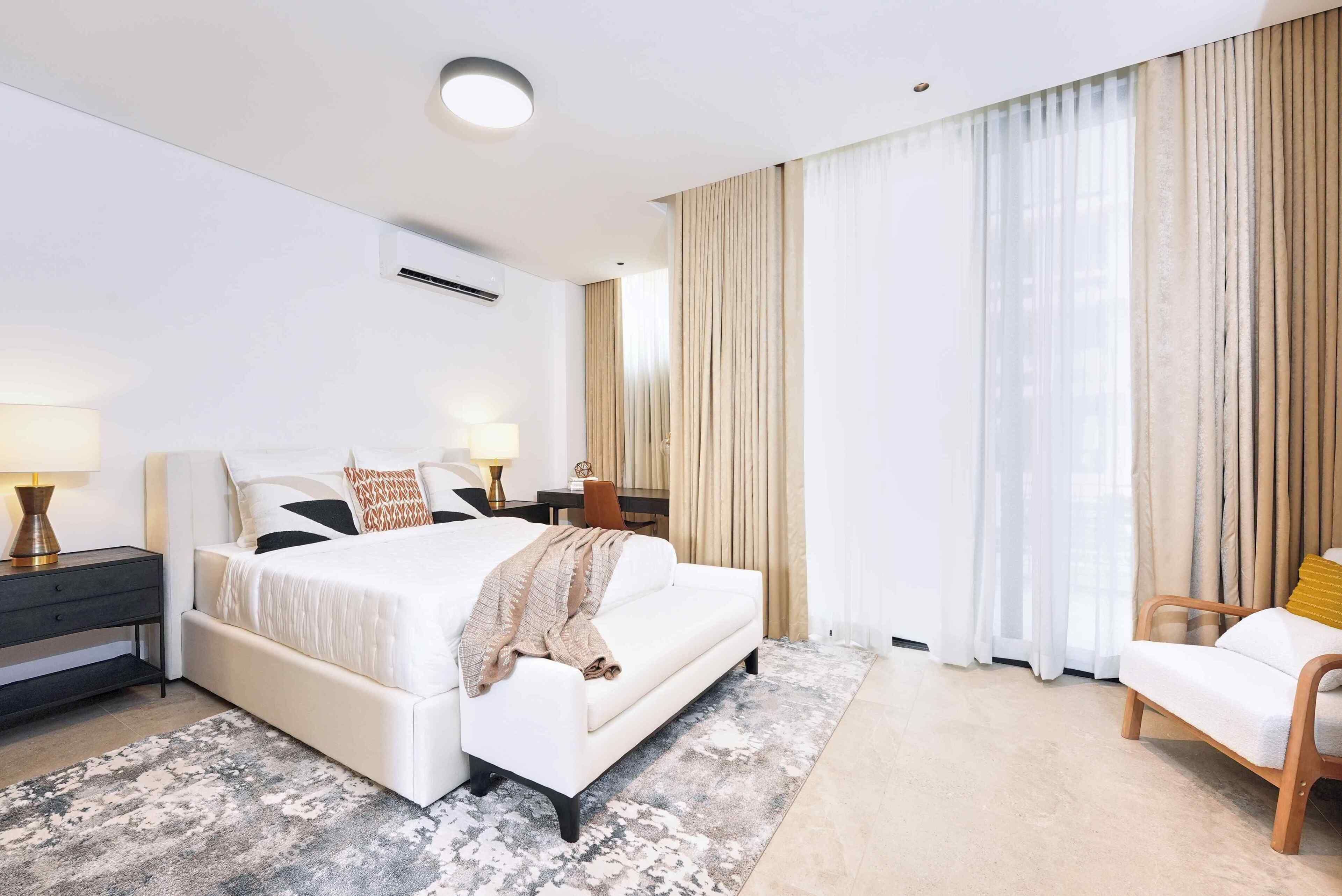 A modern bedroom with a large bed, bedside tables, a desk, and a chair.