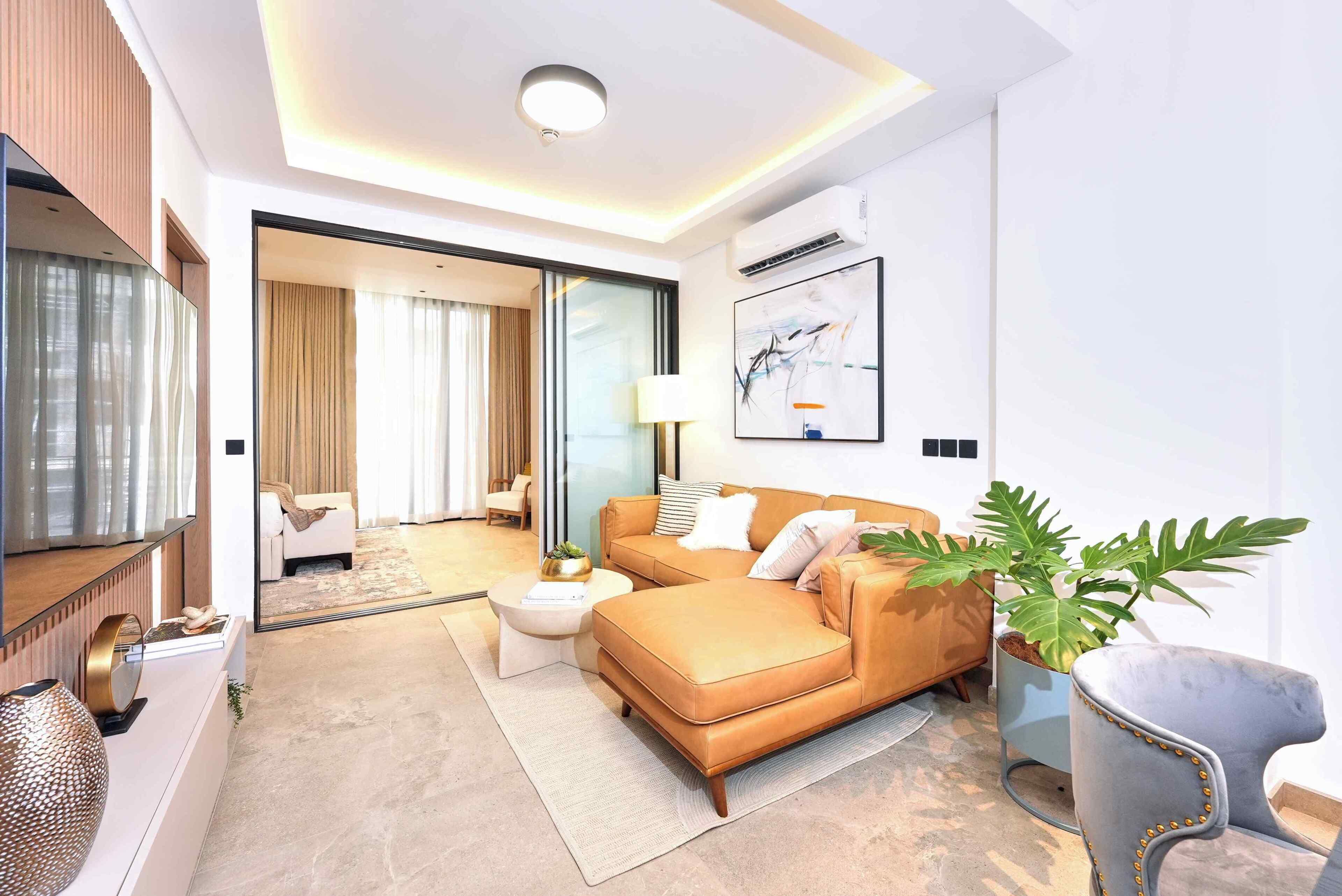 Une chambre d’hôtel moderne, équipée d’un canapé, d’une table d’appoint, d’une lampe, d’une grande fenêtre et d’une plante.