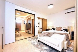 Een hotelkamer met een groot bed, een zithoek met een bank, een televisie en een badkamer met een spiegel.