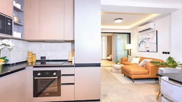 Une cuisine moderne équipée d’un four Bosch, un coin repas avec un canapé et une table basse, et un salon avec un divan et un tableau au mur.