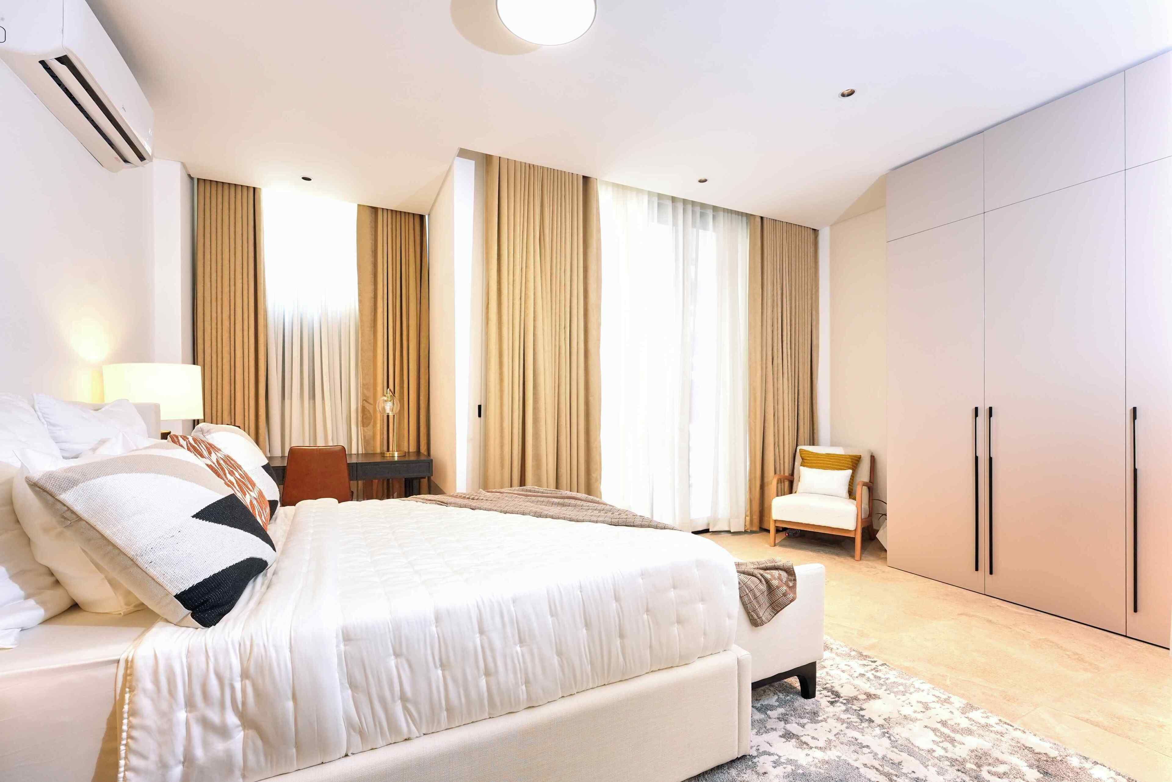 Une chambre d’hôtel avec un grand lit, un bureau, une chaise et une armoire.