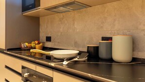 A modern kitchen with a Bosch microwave, a wooden fruit basket, a white frying pan, and a set of black and white containers. - KORE -The Milton (Accra)