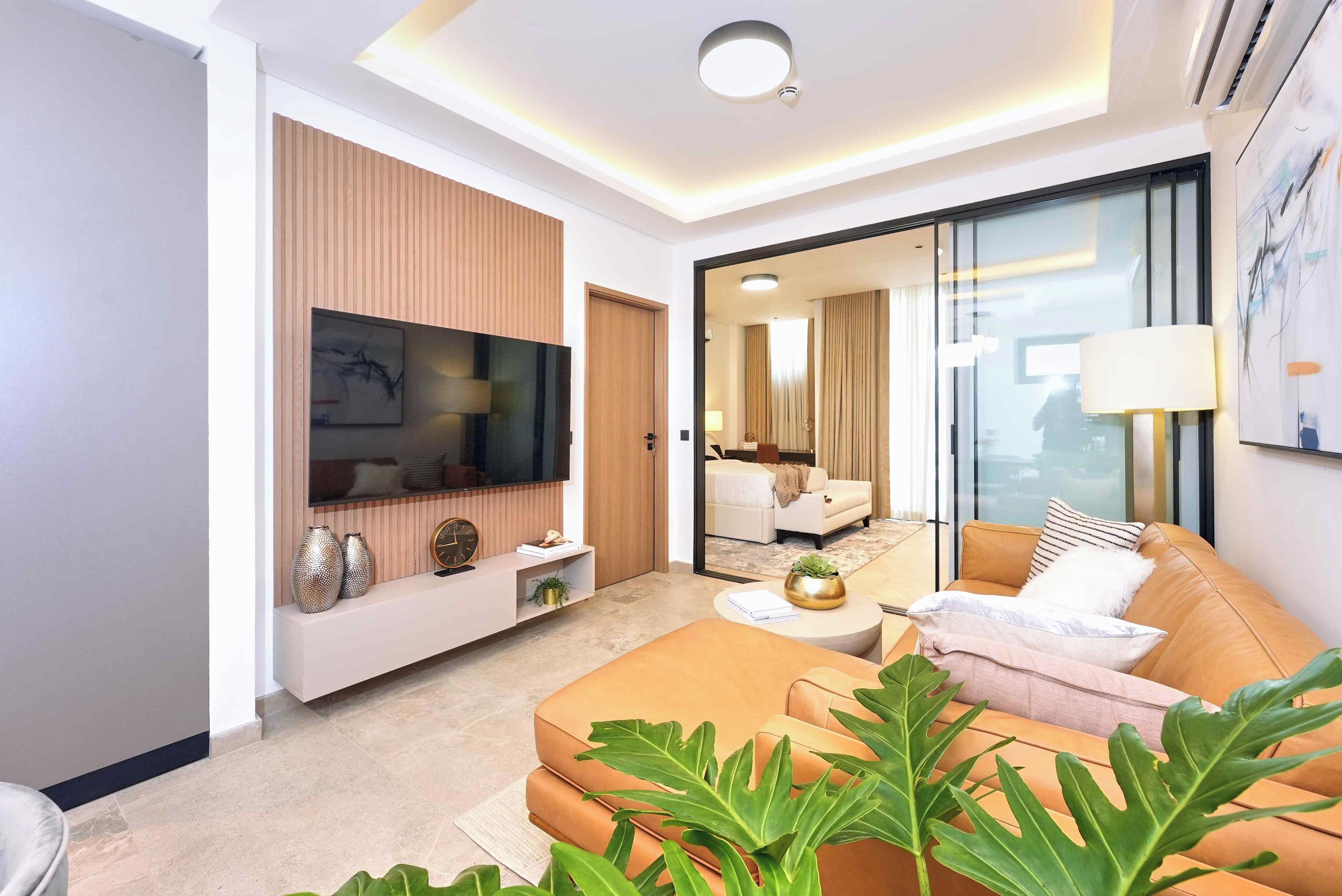 Una sala de estar moderna con un televisor de pantalla plana, un sofá, una mesa de centro y un ventanal grande.