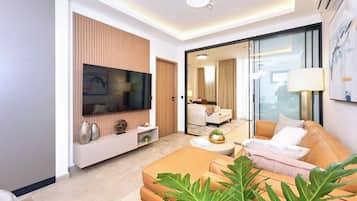A modern living room with a flat-screen TV, a sofa, a coffee table, and a large window.